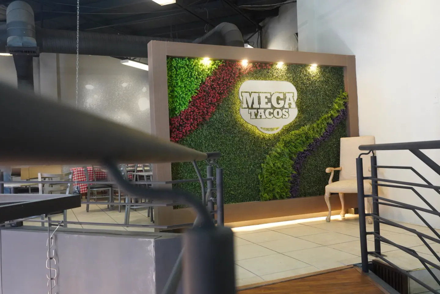 Muro verde con el logo de MegaTacos dentro del salón